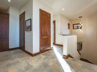 This spacious hallway features elegant wooden doors and cabinetry, complemented by a sophisticated tile floor.