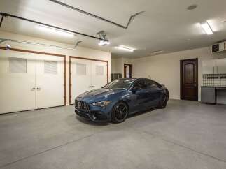 This spacious garage features a sleek, dark blue sedan parked on a clean concrete floor.