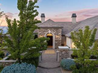 Experience luxury living in this stunning estate, featuring a grand stone-clad entrance with an arched doorway and elegant lighting.