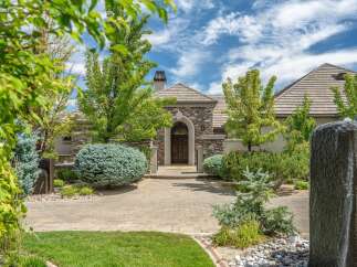 Discover this stunning home featuring a grand stone facade and an arched entryway with double wooden doors.