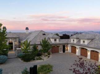 Experience luxury living in this stunning estate, featuring a grand stone-accented entrance and a spacious multi-car garage.
