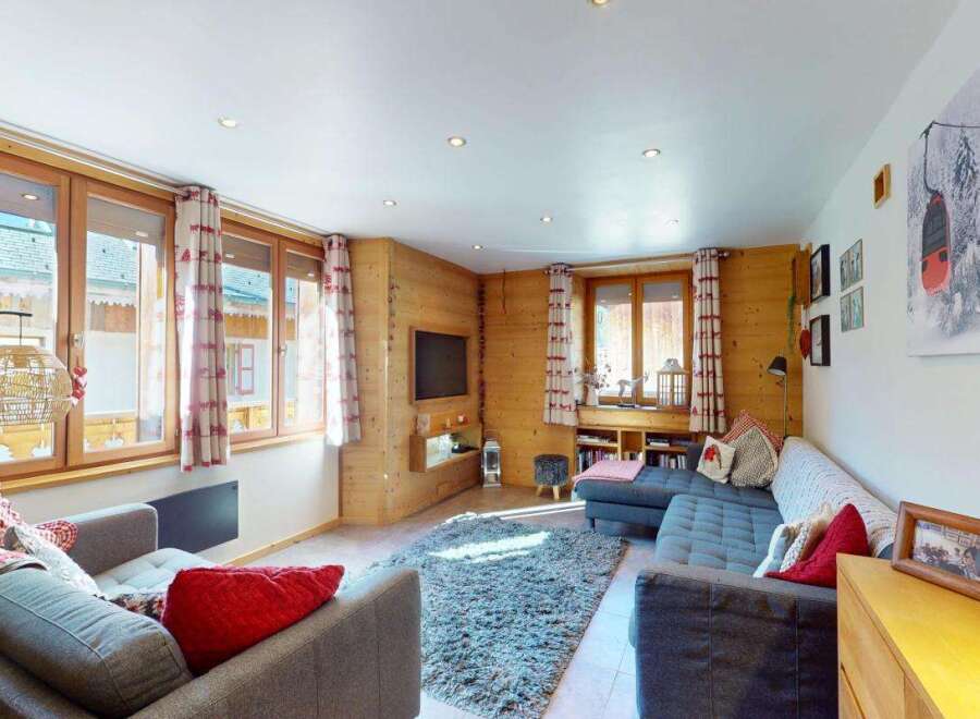 Experience cozy living in this charming mountain retreat, featuring warm wood paneling and large windows that flood the space with natural light.