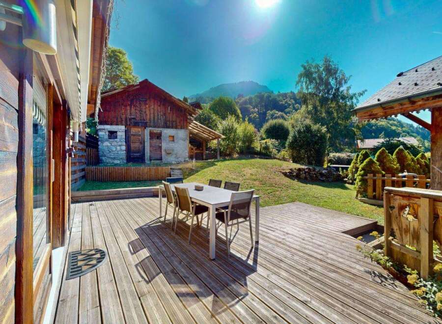 Enjoy outdoor living on this expansive wooden deck, perfect for al fresco dining with a table and chairs set.
