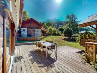 Enjoy outdoor living on this expansive wooden deck, perfect for al fresco dining with a table and chairs set.