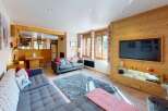 Experience cozy living in this charming mountain retreat, featuring a spacious living area with a large sectional sofa and a plush rug perfect for relaxation.