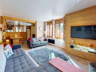 Experience cozy living in this charming mountain retreat, featuring a spacious living area with a large sectional sofa and a plush rug perfect for relaxation.
