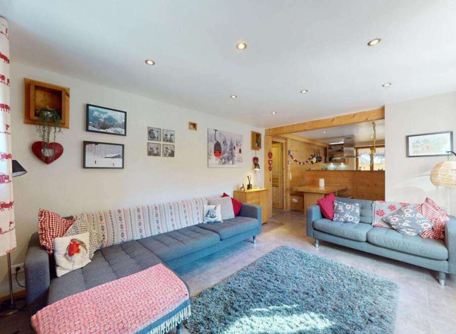 Experience cozy mountain living in this charming living room, featuring a comfortable sectional sofa adorned with festive pillows and a plush blue rug.