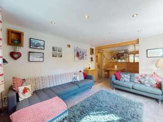Experience cozy mountain living in this charming living room, featuring a comfortable sectional sofa adorned with festive pillows and a plush blue rug.