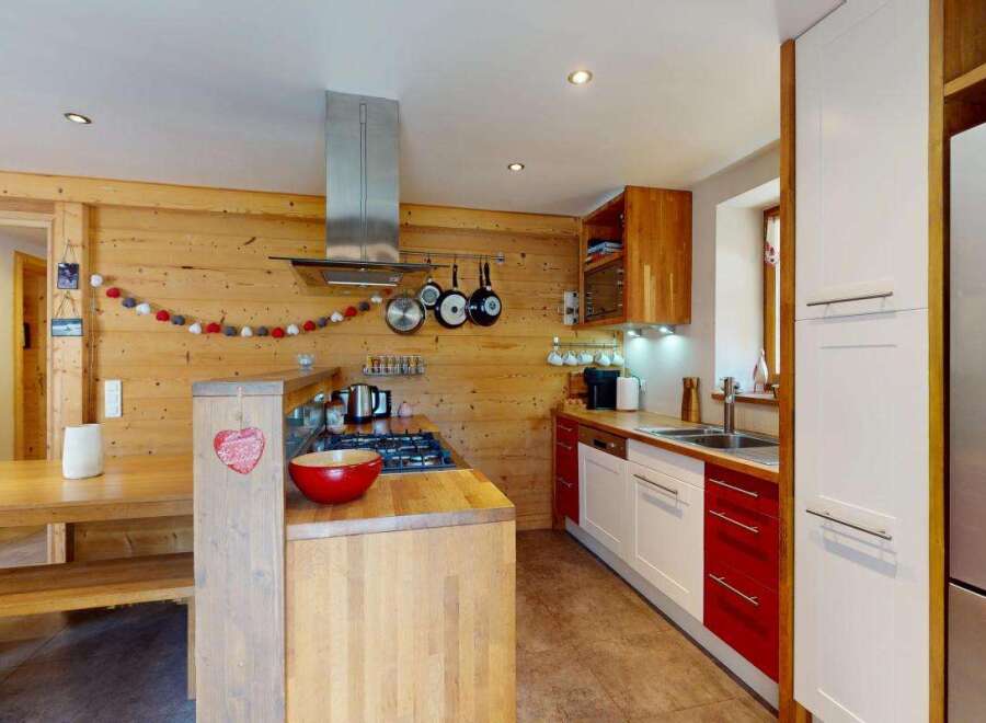 Experience cozy living in this charming kitchen featuring warm wood paneling and a rustic dining area.