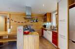 Experience cozy living in this charming kitchen featuring warm wood paneling and a rustic dining area.