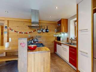 Experience cozy living in this charming kitchen featuring warm wood paneling and a rustic dining area.