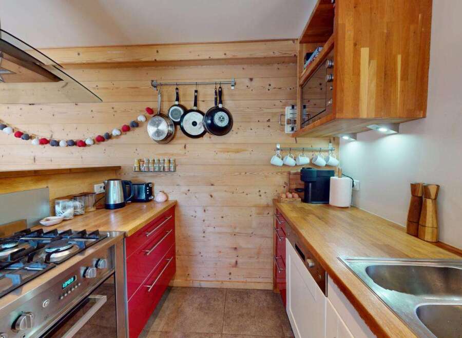 Experience rustic charm in this cozy kitchen featuring warm wooden walls and countertops.