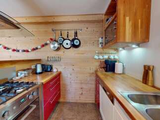 Experience rustic charm in this cozy kitchen featuring warm wooden walls and countertops.