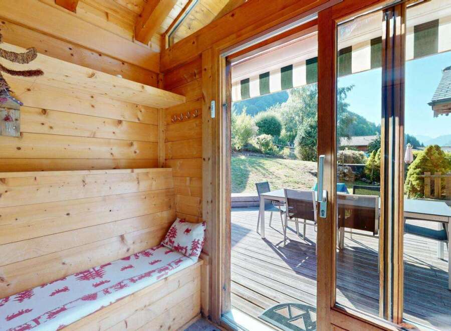 Step into this charming wooden cabin, featuring a cozy built-in bench with a festive red and white patterned cushion, perfect for relaxing after a day outdoors.