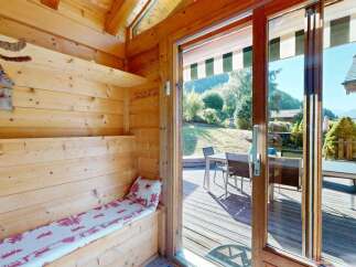 Step into this charming wooden cabin, featuring a cozy built-in bench with a festive red and white patterned cushion, perfect for relaxing after a day outdoors.