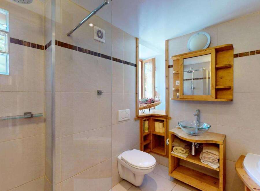 This charming bathroom features a spacious walk-in shower with glass doors and a rainfall showerhead, perfect for a relaxing experience.