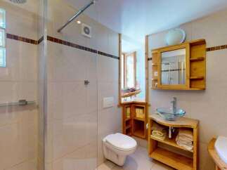 This charming bathroom features a spacious walk-in shower with glass doors and a rainfall showerhead, perfect for a relaxing experience.
