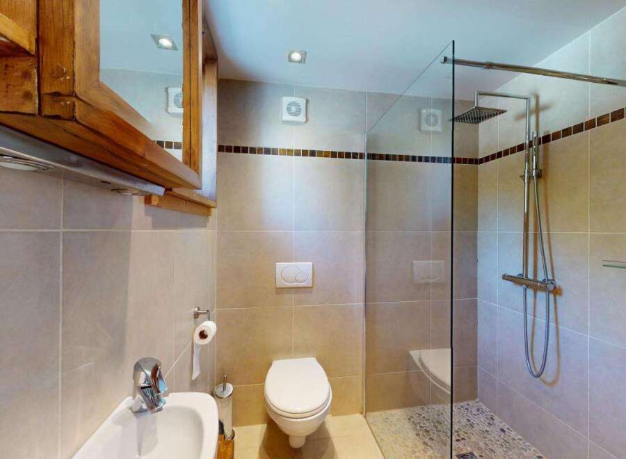 This modern bathroom features a sleek glass-enclosed shower with a rainfall showerhead, perfect for a spa-like experience.