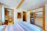 Discover this charming bedroom featuring a comfortable bed with striped linens and a convenient en-suite bathroom.
