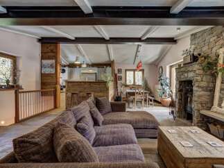 Experience rustic charm in this spacious living area, featuring a large sectional sofa perfect for gatherings and a striking stone fireplace that serves as the room's focal point.