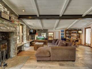 Experience rustic charm in this spacious living area, featuring a striking stone fireplace and a cozy wood-burning stove.