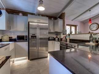 This modern kitchen boasts sleek grey cabinetry and a large stainless steel refrigerator, perfect for a busy household.