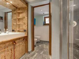 Experience rustic charm in this mountain bathroom, featuring a wooden vanity with a modern vessel sink and ample shelving.