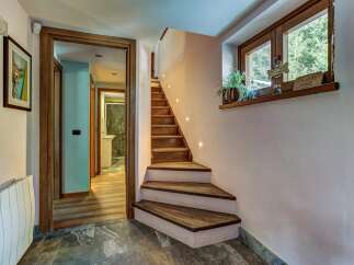 Discover this charming entryway featuring a unique wooden staircase with ambient lighting, leading to upper levels.
