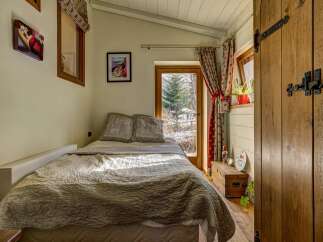 Experience cozy living in this charming bedroom, featuring a comfortable bed adorned with plush pillows and a textured quilt.