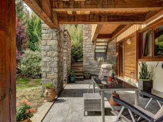Enjoy outdoor living on this charming covered patio, featuring a stone accent wall and a rustic wooden beam ceiling.
