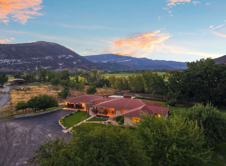 Experience serene country living with this stunning property, featuring a spacious home with a red tile roof and large windows offering breathtaking mountain views.