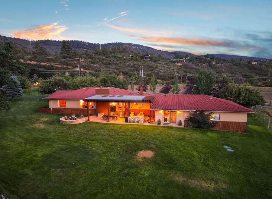 Experience breathtaking mountain views from this stunning ranch-style home, featuring a spacious covered patio perfect for entertaining and a cozy fire pit area for evening relaxation.