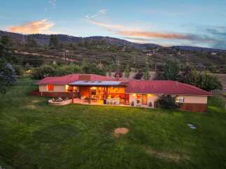 Experience breathtaking mountain views from this stunning ranch-style home, featuring a spacious covered patio perfect for entertaining and a cozy fire pit area for evening relaxation.