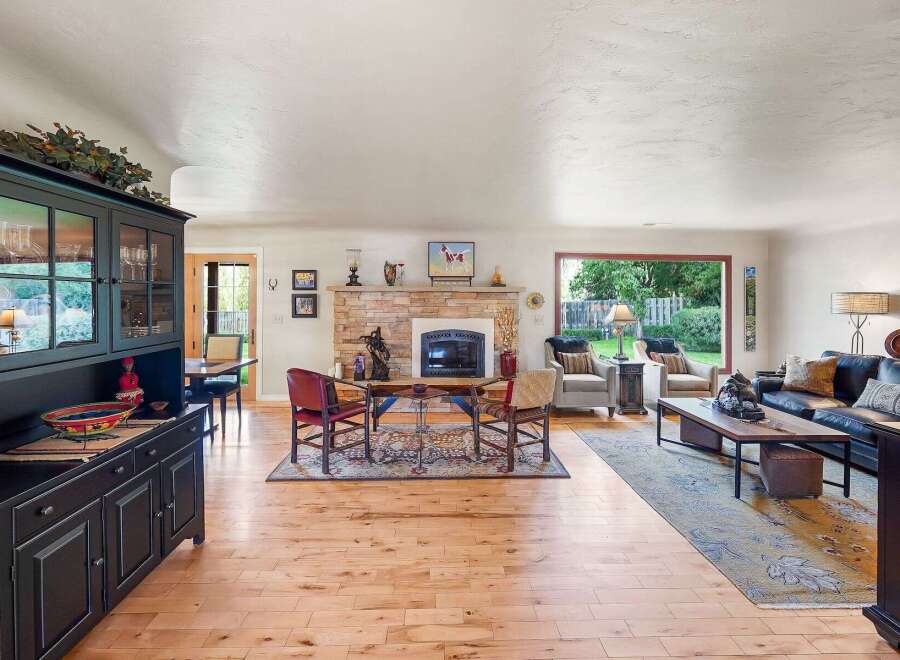 Step into this inviting living room, featuring a striking stone fireplace as the focal point and a large window offering serene backyard views.