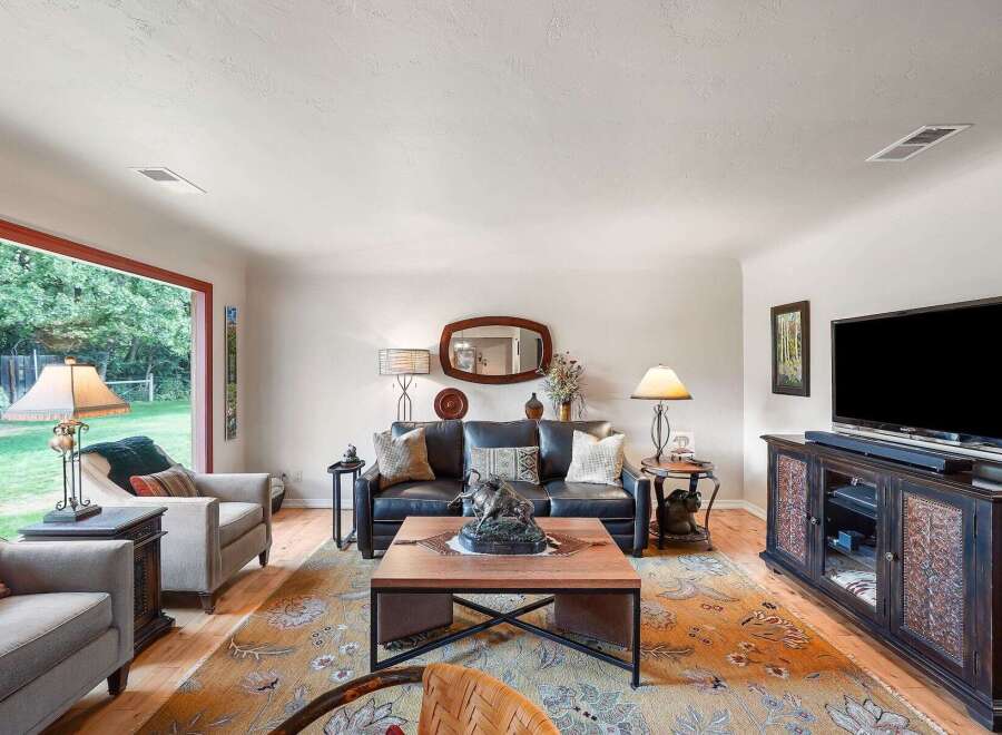 Step into this inviting living room, bathed in natural light from a large picture window overlooking a lush backyard.