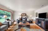 Step into this inviting living room, bathed in natural light from a large picture window overlooking a lush backyard.