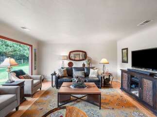 Step into this inviting living room, bathed in natural light from a large picture window overlooking a lush backyard.
