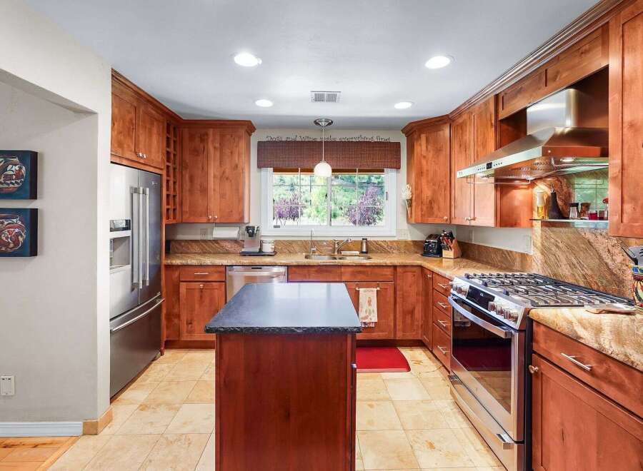 This beautifully appointed kitchen features rich cherry wood cabinetry and granite countertops, offering a warm and inviting atmosphere.