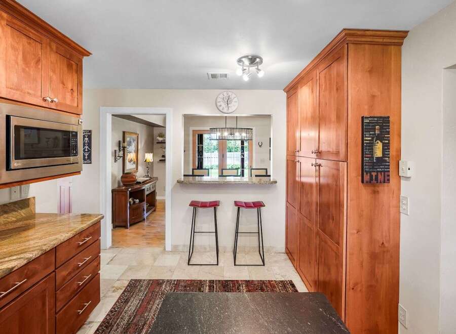 This spacious kitchen features warm cherry wood cabinetry, including a tall pantry and overhead microwave cabinet.