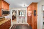 This spacious kitchen features warm cherry wood cabinetry, including a tall pantry and overhead microwave cabinet.