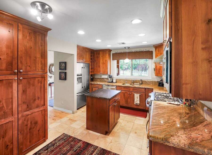 This spacious kitchen boasts rich cherry wood cabinetry, granite countertops, and a central island perfect for meal preparation.