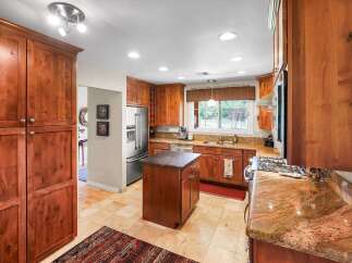 This spacious kitchen boasts rich cherry wood cabinetry, granite countertops, and a central island perfect for meal preparation.