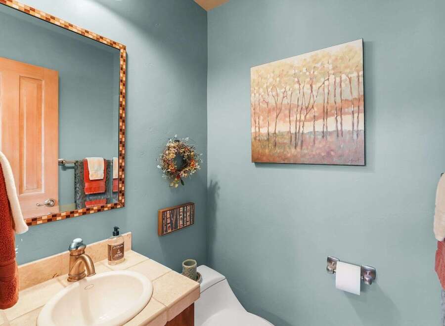 This powder room features a stylish vanity with a stone countertop and a modern brass faucet, complemented by a decorative mosaic mirror.