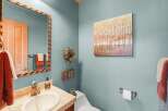 This powder room features a stylish vanity with a stone countertop and a modern brass faucet, complemented by a decorative mosaic mirror.