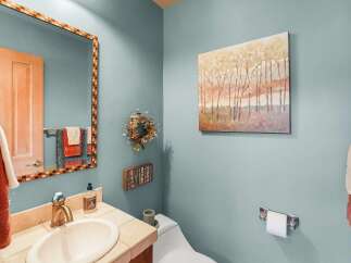 This powder room features a stylish vanity with a stone countertop and a modern brass faucet, complemented by a decorative mosaic mirror.
