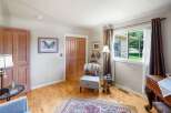Step into this charming room featuring a cozy armchair and a decorative rug, perfect for relaxation.
