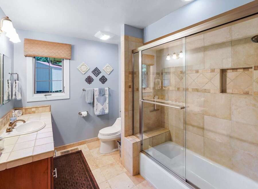 This charming bathroom features a spacious vanity with a tiled countertop and a large mirror, perfect for your morning routine.