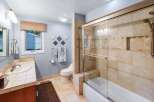 This charming bathroom features a spacious vanity with a tiled countertop and a large mirror, perfect for your morning routine.