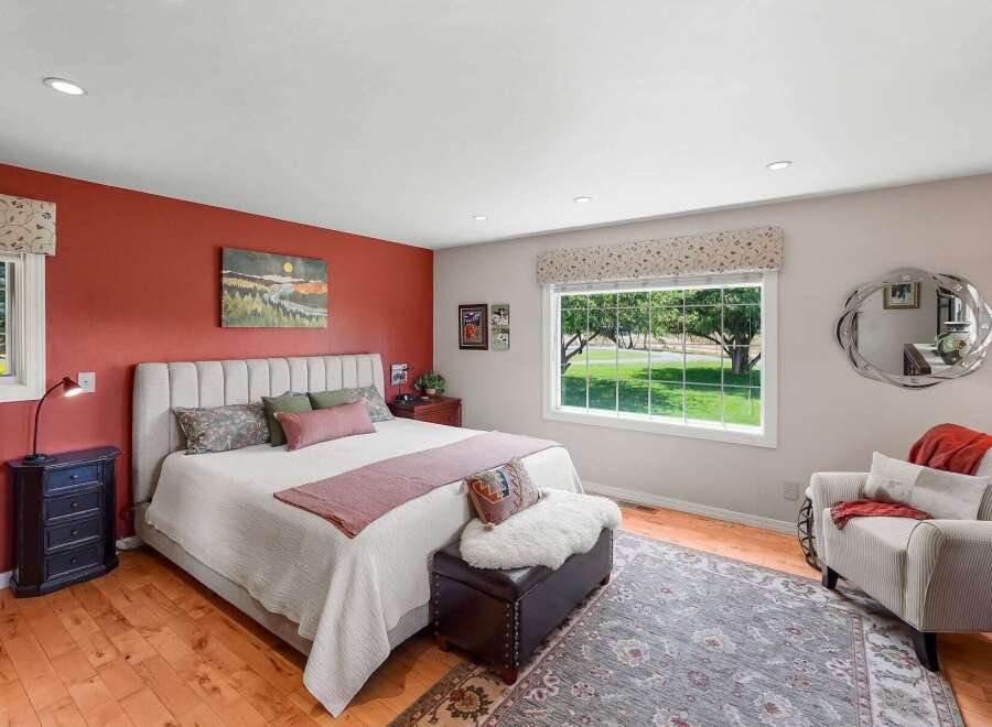 Experience serene living in this charming bedroom featuring a plush upholstered headboard and a vibrant accent wall.