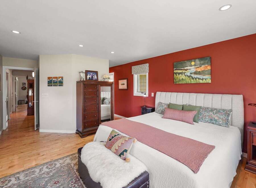 Experience comfort and style in this inviting bedroom, featuring a striking accent wall in a rich, warm hue.